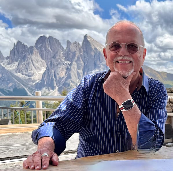 Michael Joseph Stumpf seated at a table outdoors with the Dolomites behind him