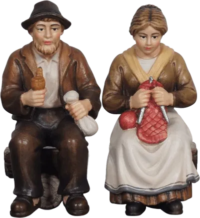 Hand-carved wooden figures of elderly man and woman seated on a bench, painted in traditional clothing